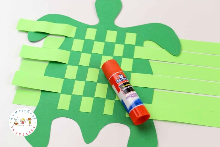 green DIY sea turtle craft with paper woven in the slits